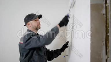 有经验的工人正在房子里做装修。 他正在用滚筒来装饰前墙。
